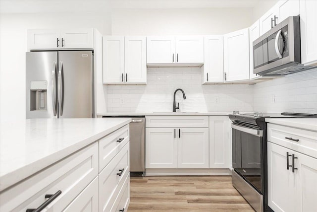 kitchen with light wood-type flooring, white cabinets, sink, and stainless steel appliances