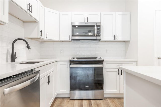 kitchen featuring light hardwood / wood-style floors, white cabinets, decorative backsplash, sink, and appliances with stainless steel finishes