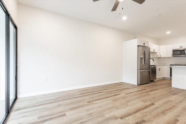 kitchen featuring stainless steel appliances, ceiling fan, light hardwood / wood-style flooring, white cabinets, and decorative backsplash