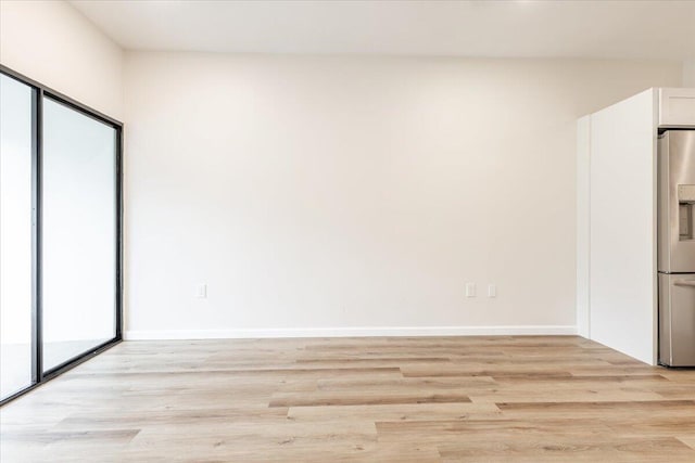 unfurnished bedroom featuring light wood-type flooring and stainless steel fridge