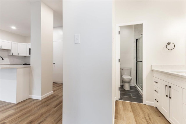 bathroom with hardwood / wood-style floors, decorative backsplash, vanity, and toilet