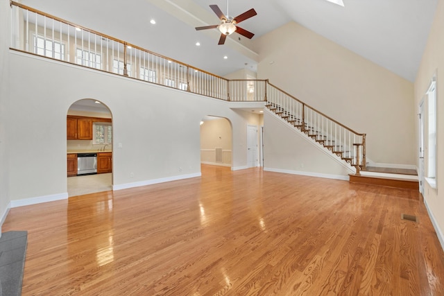 unfurnished living room featuring ceiling fan, light wood-type flooring, and high vaulted ceiling