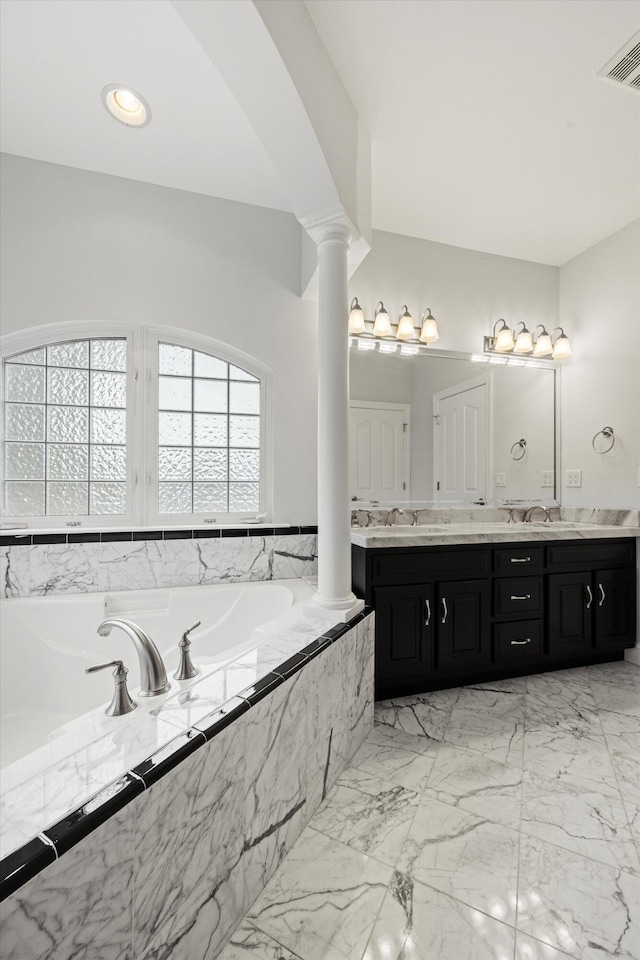 bathroom featuring vanity, tiled bath, and decorative columns