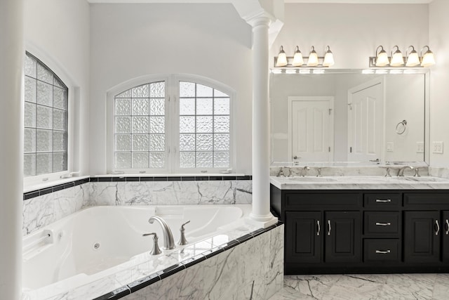 bathroom with vanity, ornate columns, and tiled tub