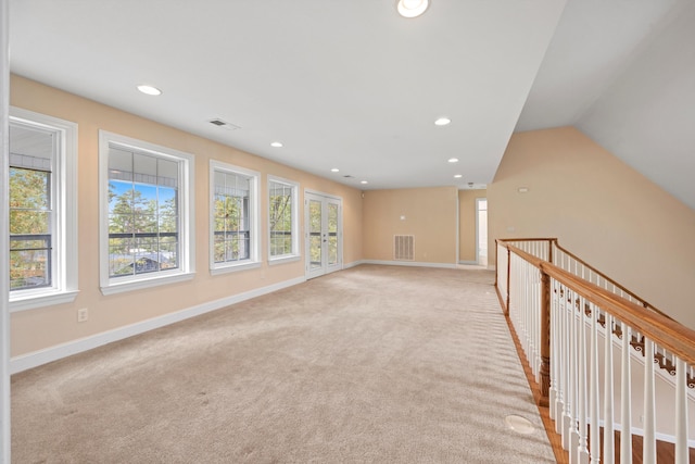 spare room featuring light colored carpet and lofted ceiling