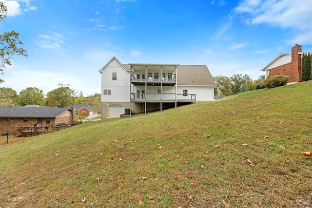 back of property with a balcony, a garage, and a lawn