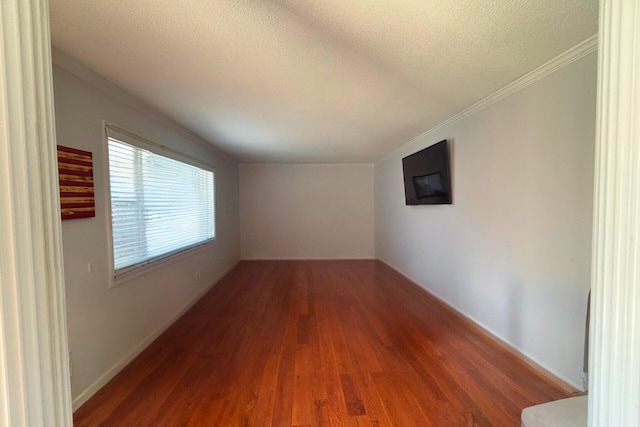 empty room with a textured ceiling, ornamental molding, and wood finished floors