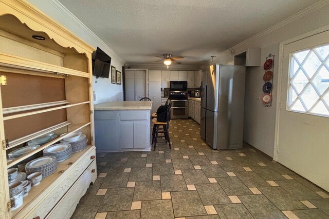 kitchen featuring ornamental molding, a peninsula, appliances with stainless steel finishes, and light countertops