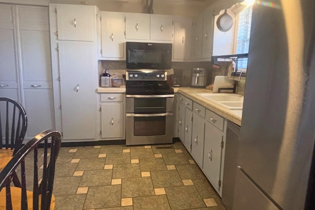 kitchen with a sink, stainless steel appliances, light countertops, and white cabinets