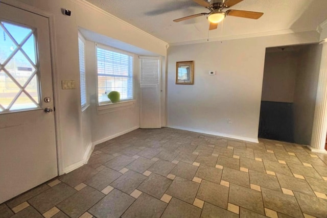 foyer with plenty of natural light, baseboards, ceiling fan, and crown molding