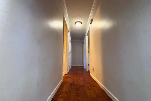 hallway with a textured ceiling, baseboards, and wood finished floors