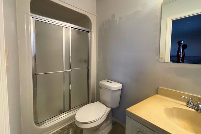 bathroom featuring toilet, a shower stall, and vanity