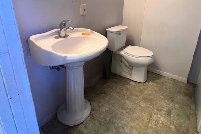 half bath with baseboards and toilet