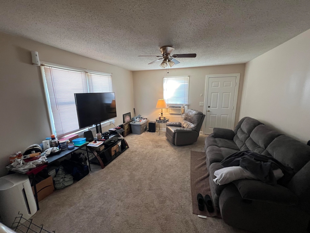 living room with cooling unit, a textured ceiling, ceiling fan, and carpet floors