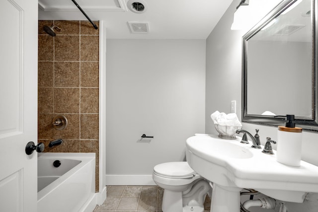 bathroom with tile patterned flooring, toilet, and tiled shower / bath combo