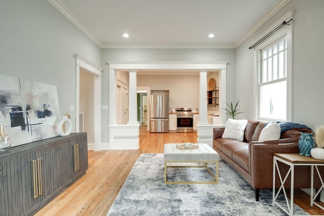 living room featuring ornate columns, light wood-type flooring, and ornamental molding