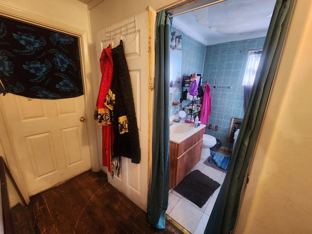 bathroom featuring toilet, a shower with curtain, wood finished floors, vanity, and tile walls