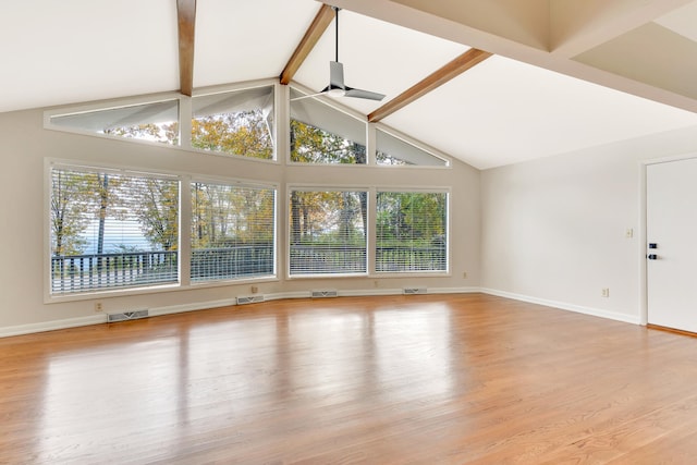 unfurnished living room featuring beamed ceiling, ceiling fan, plenty of natural light, and light hardwood / wood-style flooring