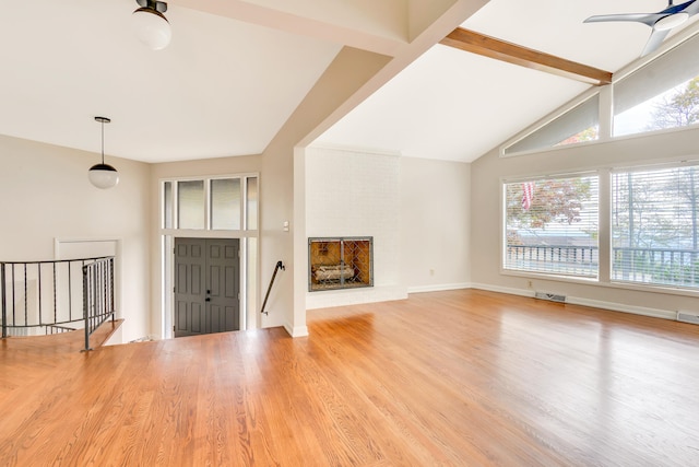 unfurnished living room featuring a brick fireplace, light hardwood / wood-style flooring, and vaulted ceiling with beams