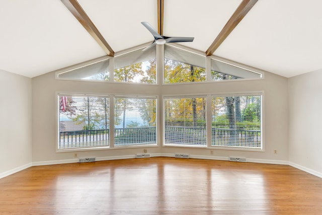 empty room featuring light wood-type flooring, a wealth of natural light, ceiling fan, and beam ceiling