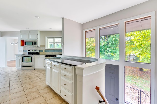 kitchen featuring white cabinets, appliances with stainless steel finishes, light tile patterned floors, and tasteful backsplash