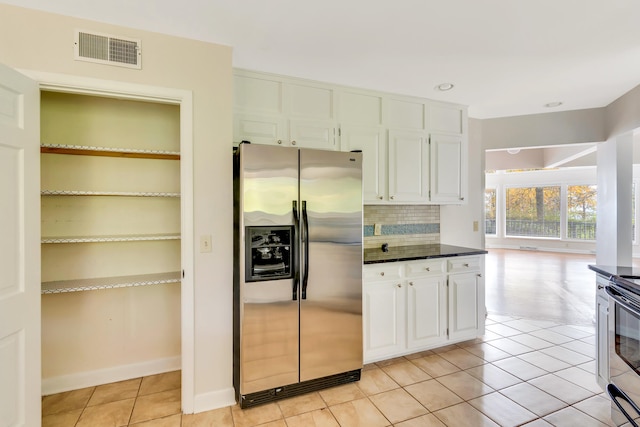 kitchen with white cabinetry, stainless steel appliances, light tile patterned floors, and tasteful backsplash