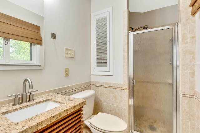 bathroom with tile walls, an enclosed shower, vanity, and toilet