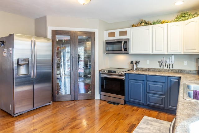 kitchen featuring white cabinetry, blue cabinetry, light hardwood / wood-style floors, and stainless steel appliances