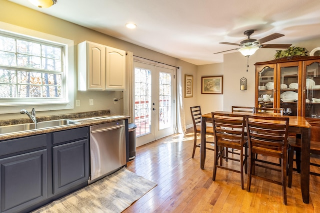 kitchen with stainless steel dishwasher, a wealth of natural light, sink, and white cabinets