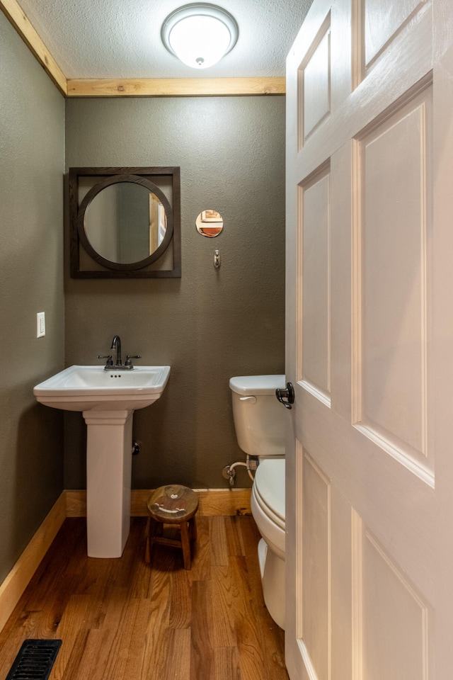 bathroom featuring a textured ceiling, hardwood / wood-style flooring, toilet, and sink