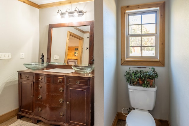 bathroom with toilet, vanity, and ornamental molding