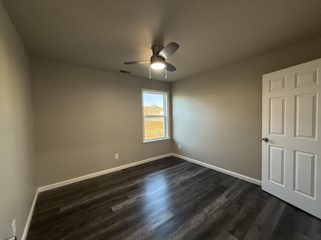 empty room featuring a ceiling fan, dark wood finished floors, visible vents, and baseboards