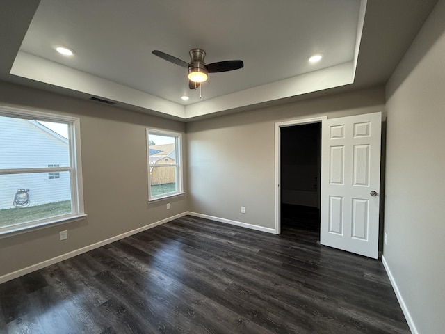 unfurnished bedroom featuring a tray ceiling, visible vents, and baseboards