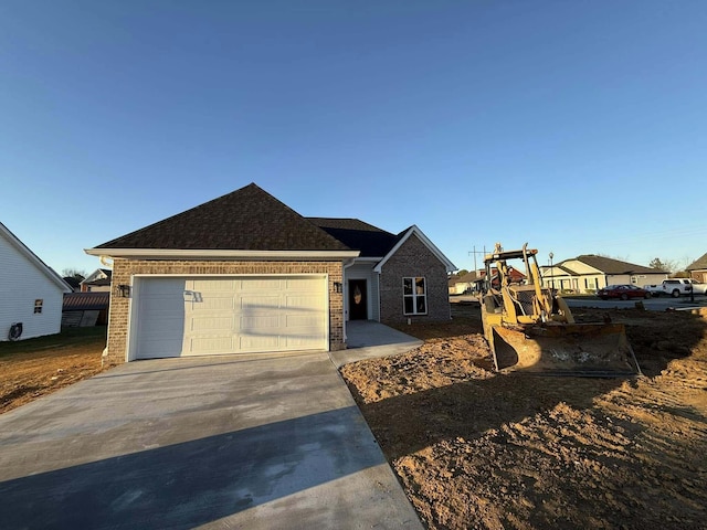 single story home featuring driveway, an attached garage, and brick siding