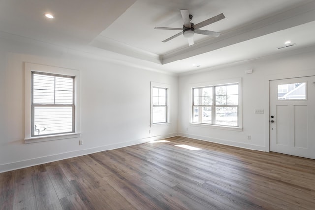 interior space with crown molding, a tray ceiling, dark wood-type flooring, and ceiling fan