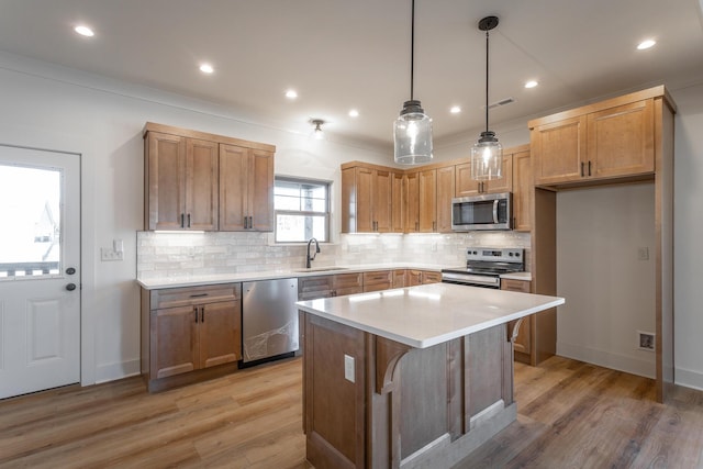 kitchen with sink, light hardwood / wood-style flooring, appliances with stainless steel finishes, a kitchen island, and decorative light fixtures