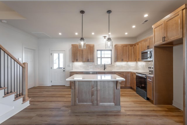 kitchen featuring appliances with stainless steel finishes, decorative light fixtures, sink, decorative backsplash, and a center island