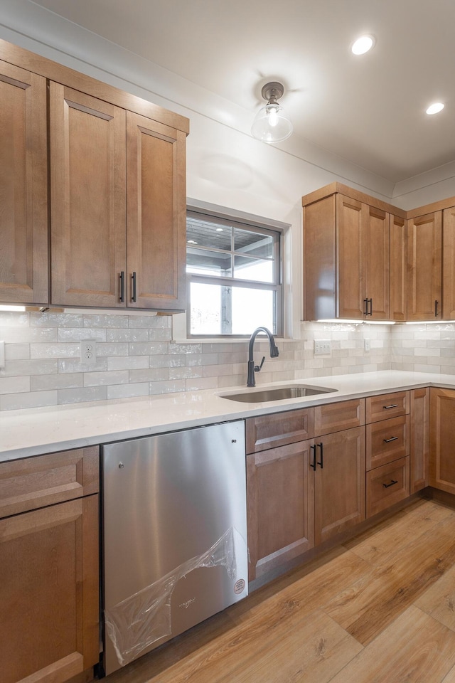 kitchen featuring dishwasher, sink, backsplash, and light wood-type flooring