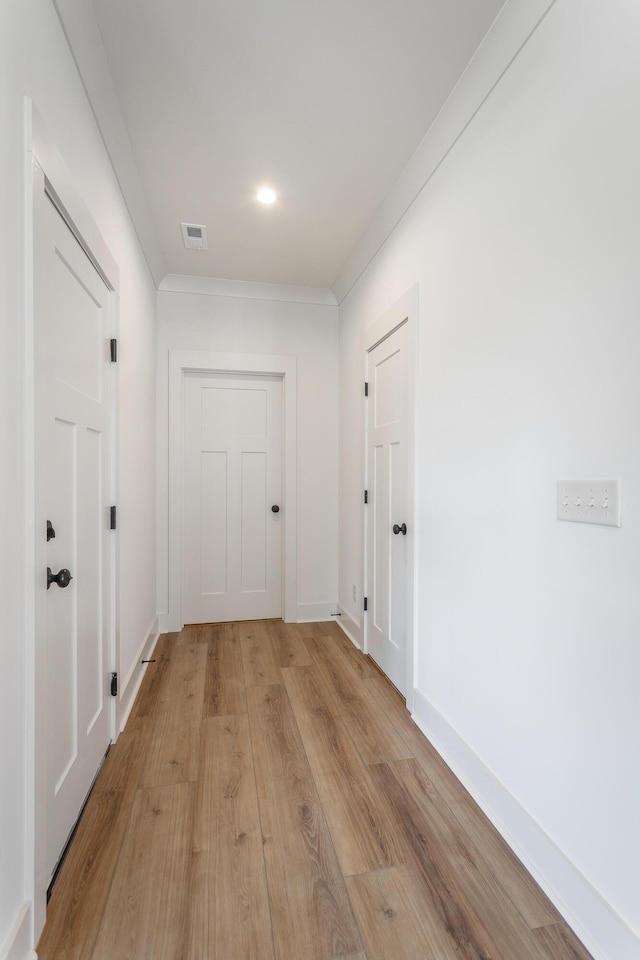 hallway featuring ornamental molding and light hardwood / wood-style floors