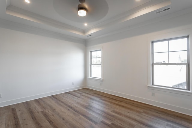 empty room featuring crown molding, a tray ceiling, wood-type flooring, and ceiling fan