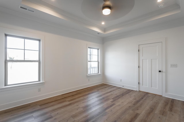 unfurnished room featuring hardwood / wood-style flooring, ceiling fan, a tray ceiling, and crown molding