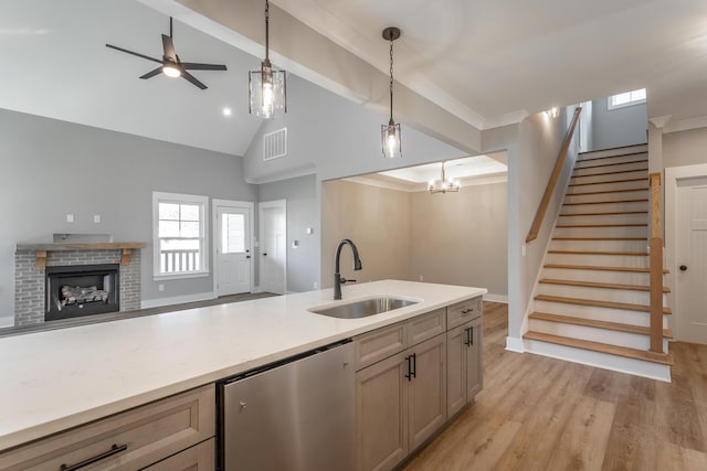 kitchen featuring decorative light fixtures, dishwashing machine, sink, and light wood-type flooring