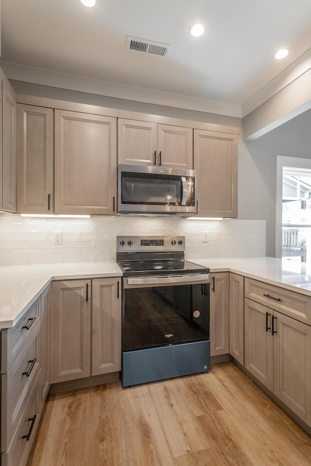 kitchen featuring backsplash, ornamental molding, light hardwood / wood-style floors, and appliances with stainless steel finishes