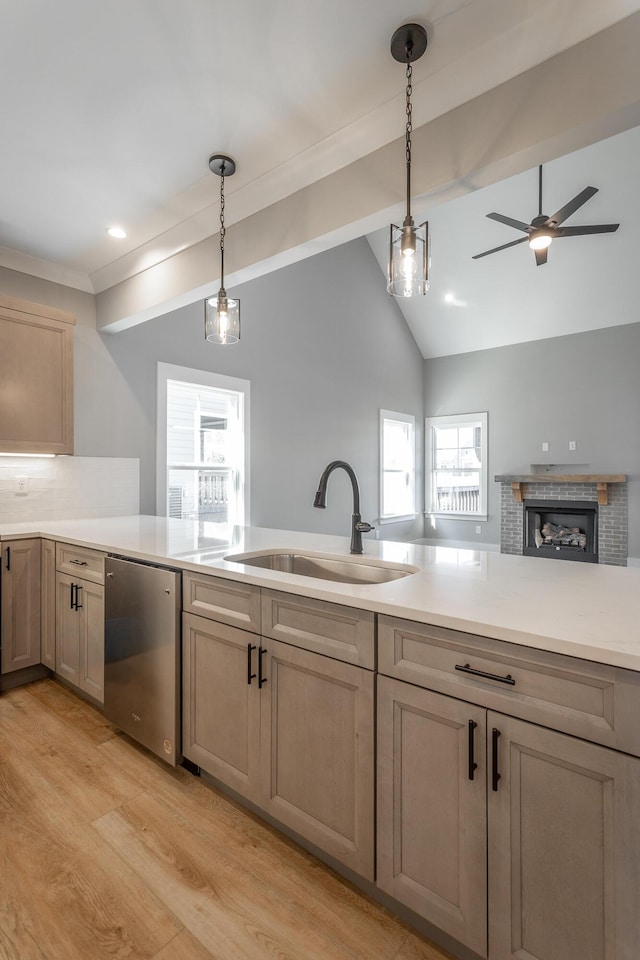 kitchen featuring sink, light hardwood / wood-style flooring, dishwasher, hanging light fixtures, and vaulted ceiling