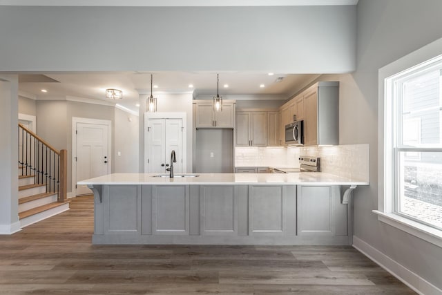 kitchen featuring sink, backsplash, stainless steel appliances, decorative light fixtures, and kitchen peninsula