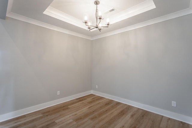 unfurnished room featuring ornamental molding, hardwood / wood-style floors, an inviting chandelier, and a tray ceiling