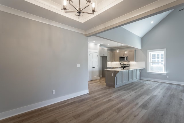 kitchen featuring hardwood / wood-style floors, decorative light fixtures, backsplash, a chandelier, and kitchen peninsula