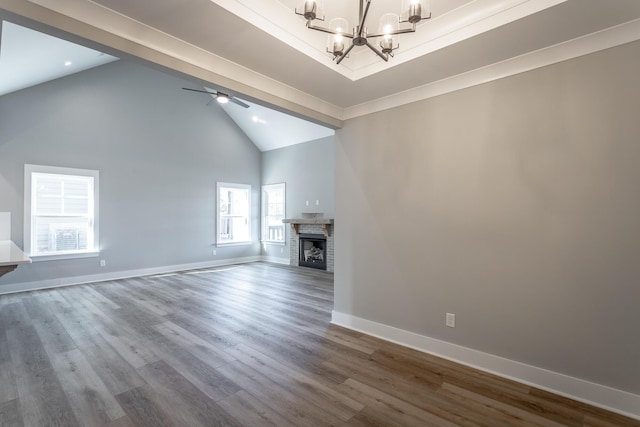 unfurnished living room featuring a brick fireplace, hardwood / wood-style flooring, ceiling fan with notable chandelier, and high vaulted ceiling