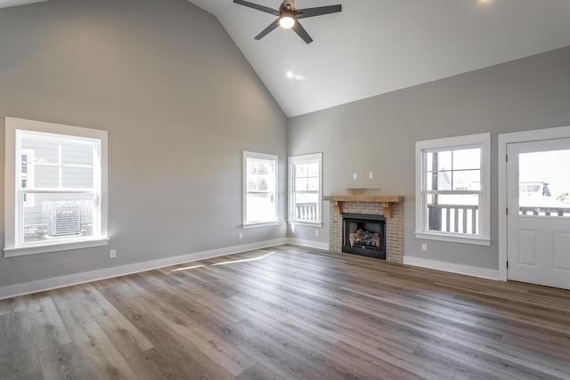 unfurnished living room with ceiling fan, high vaulted ceiling, a fireplace, and light wood-type flooring