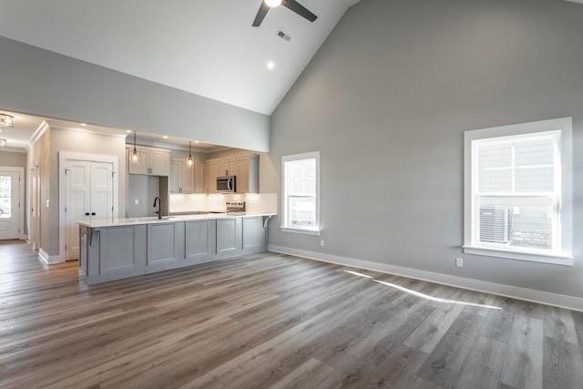 kitchen with pendant lighting, high vaulted ceiling, sink, kitchen peninsula, and stainless steel appliances